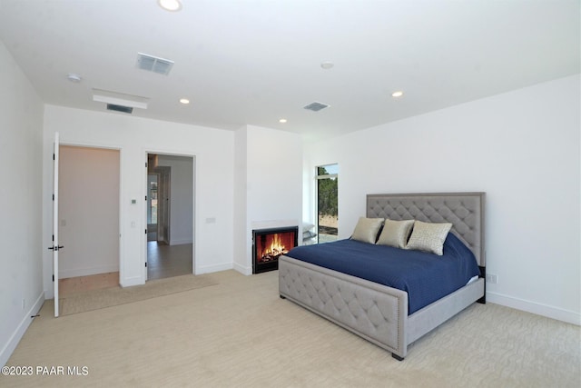 carpeted bedroom featuring a warm lit fireplace, visible vents, and recessed lighting