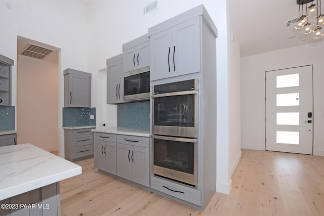 kitchen featuring stainless steel appliances, visible vents, light wood-style flooring, and gray cabinetry