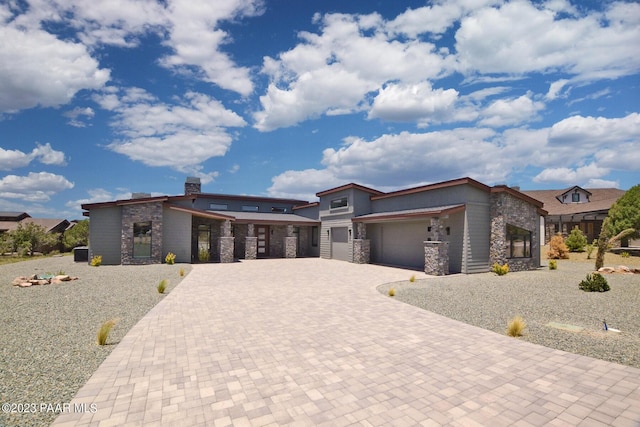 view of front of property featuring decorative driveway, stone siding, and an attached garage