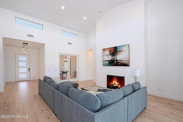 living room featuring a wealth of natural light, visible vents, a lit fireplace, and light wood finished floors