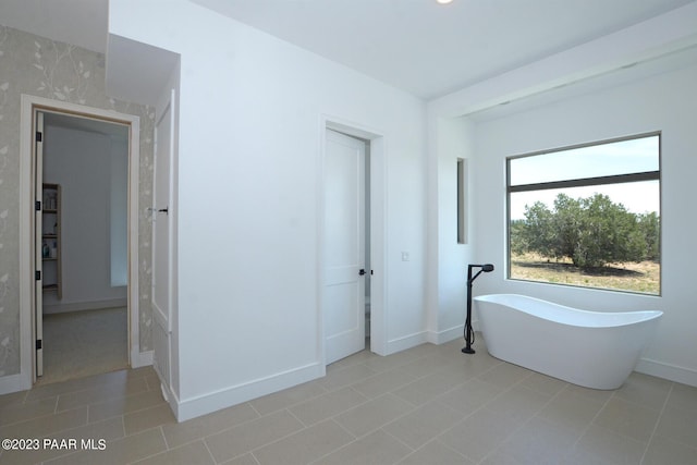 full bathroom featuring tile patterned flooring, a freestanding bath, and baseboards