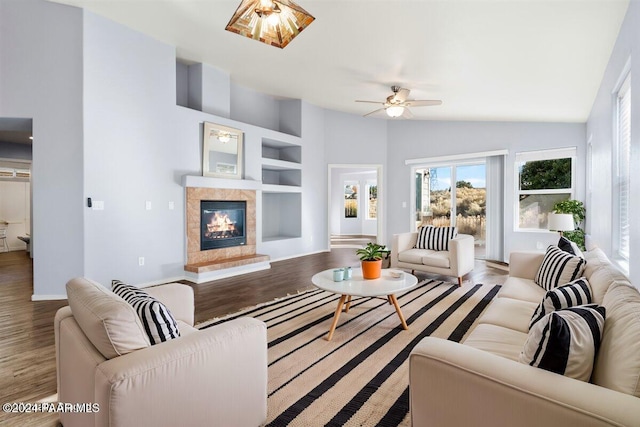 living room featuring built in features, hardwood / wood-style flooring, vaulted ceiling, and ceiling fan