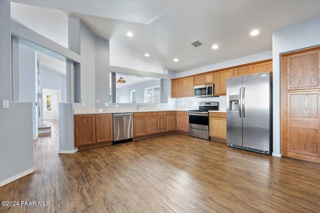 kitchen featuring high vaulted ceiling, wood-type flooring, sink, and appliances with stainless steel finishes