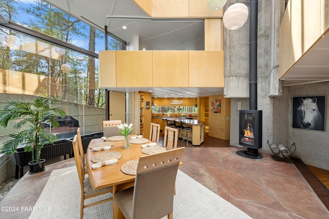 dining space featuring a high ceiling, a wood stove, and a wall of windows