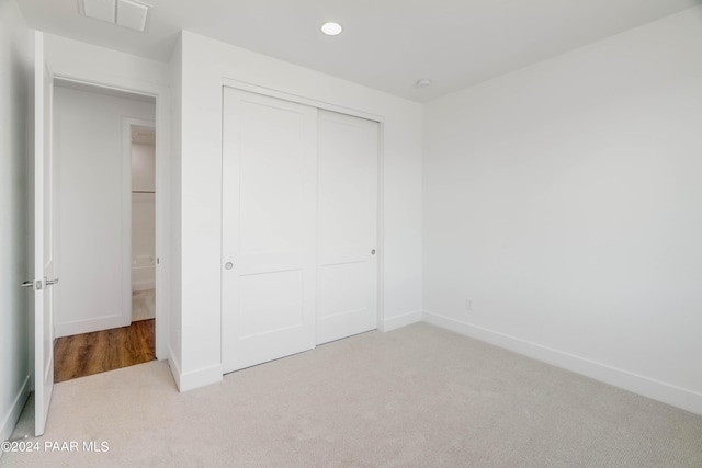 unfurnished bedroom with light carpet and a closet