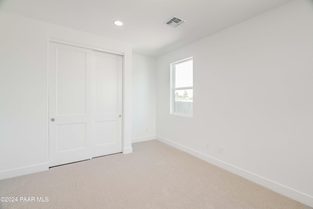 unfurnished bedroom featuring light carpet and a closet