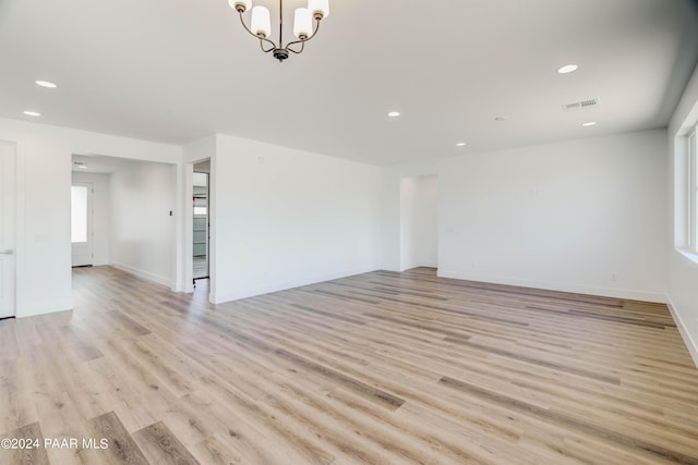 unfurnished room with light hardwood / wood-style floors and a notable chandelier