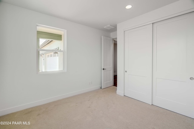 unfurnished bedroom with light carpet and a closet