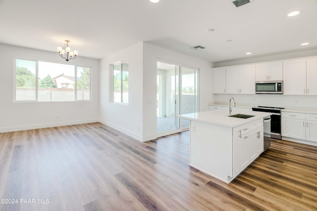 kitchen featuring appliances with stainless steel finishes, sink, light hardwood / wood-style flooring, white cabinets, and an island with sink