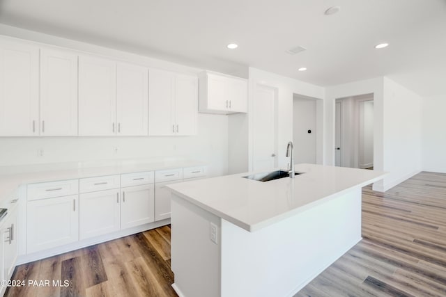 kitchen featuring white cabinetry, a center island with sink, light hardwood / wood-style floors, and sink