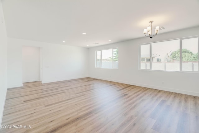 unfurnished room with light hardwood / wood-style floors and an inviting chandelier