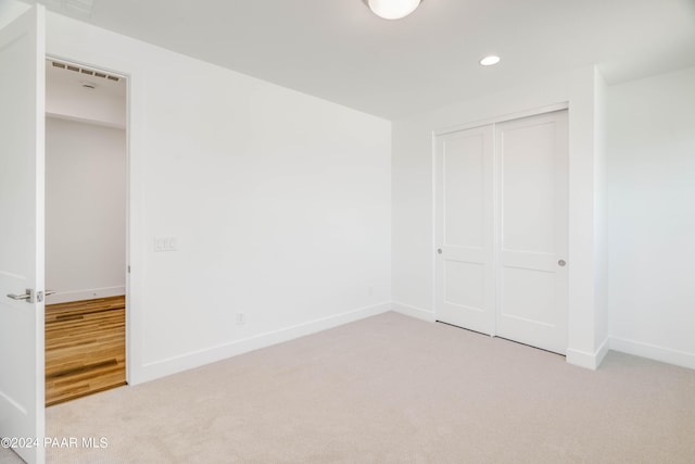 unfurnished bedroom featuring light carpet and a closet