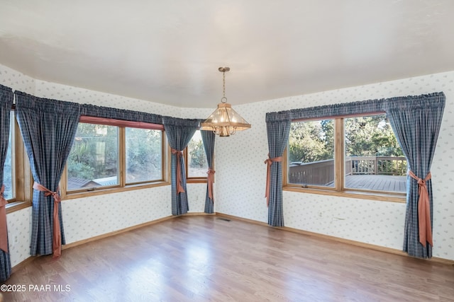 1104 Country Club Dr, Prescott, AZ 86303 - spare room with wallpapered walls, wood finished floors, a chandelier, and baseboards