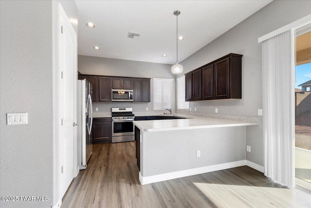 kitchen with pendant lighting, kitchen peninsula, a healthy amount of sunlight, and appliances with stainless steel finishes