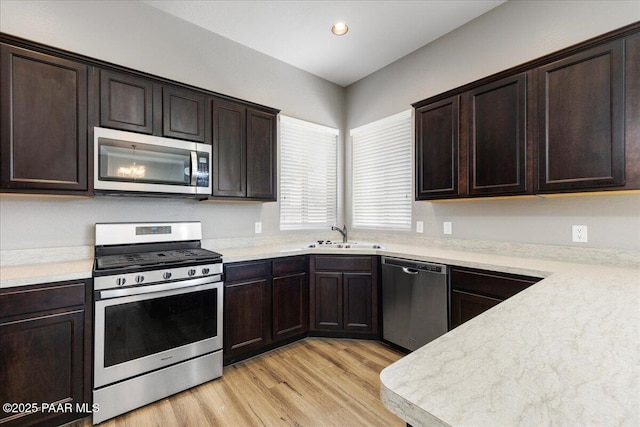 kitchen with dark brown cabinetry, stainless steel appliances, sink, and light hardwood / wood-style flooring