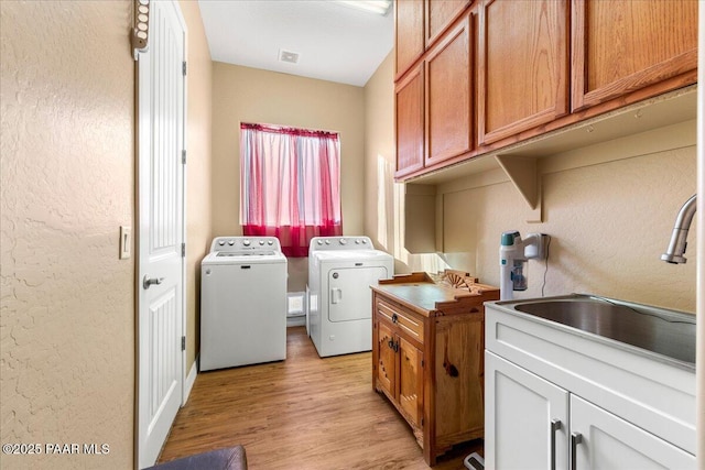 laundry room featuring light wood-type flooring, independent washer and dryer, and sink