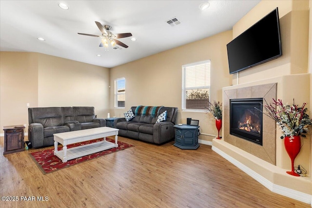 living room with ceiling fan, a fireplace, and hardwood / wood-style flooring