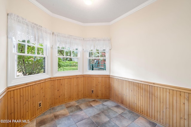 spare room with a textured ceiling, crown molding, and wood walls