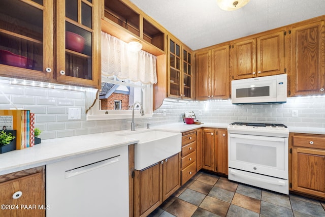 kitchen featuring a textured ceiling, decorative backsplash, sink, and white appliances