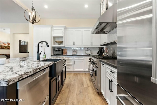 kitchen with white cabinetry, island range hood, hanging light fixtures, dark stone countertops, and stainless steel appliances