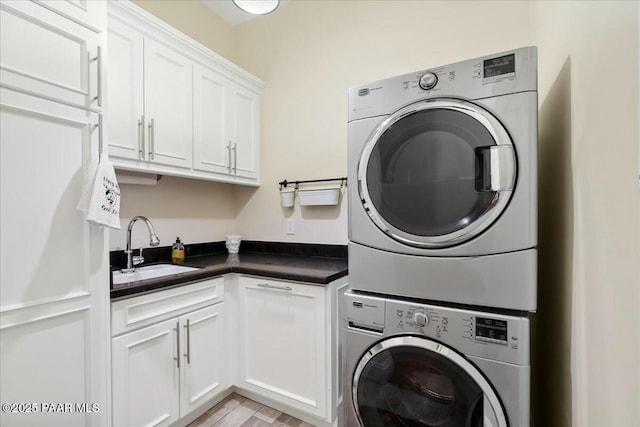 laundry area featuring light hardwood / wood-style floors, sink, cabinets, and stacked washer and clothes dryer