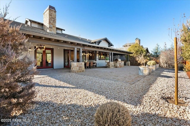 rear view of property with a patio and an outdoor kitchen