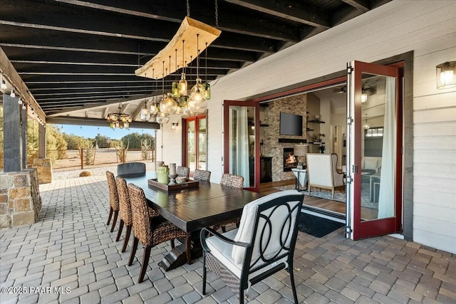 dining area with beamed ceiling, exterior fireplace, and wood walls