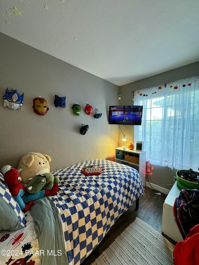 bedroom with dark hardwood / wood-style floors and a textured ceiling