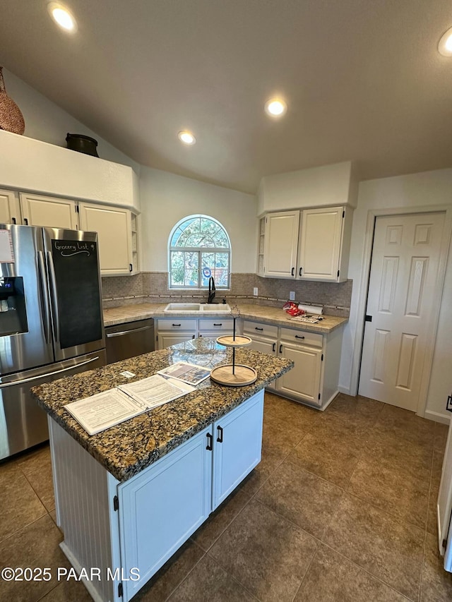 kitchen with appliances with stainless steel finishes, sink, a kitchen island, and white cabinets