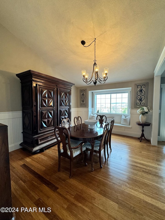 dining room featuring an inviting chandelier, wood-type flooring, and a textured ceiling