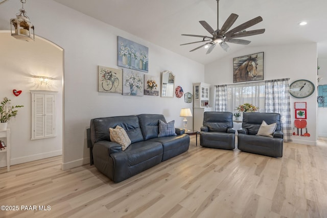 living area with baseboards, a ceiling fan, vaulted ceiling, and light wood finished floors