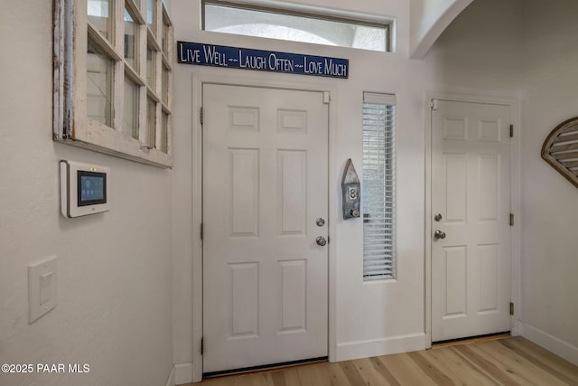 entrance foyer with baseboards, arched walkways, and wood finished floors