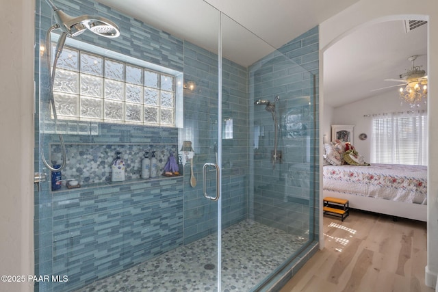 ensuite bathroom featuring ceiling fan, lofted ceiling, a stall shower, wood finished floors, and ensuite bath