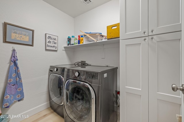 laundry area with visible vents, washer and dryer, wood finished floors, cabinet space, and baseboards