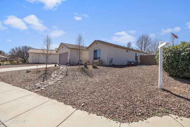 ranch-style house featuring concrete driveway, an attached garage, and stucco siding