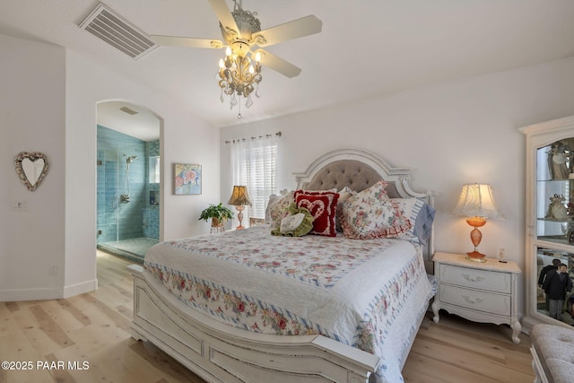 bedroom featuring baseboards, visible vents, arched walkways, ensuite bathroom, and light wood-type flooring