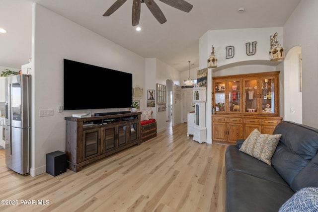 living room with a ceiling fan, lofted ceiling, light wood-style flooring, recessed lighting, and arched walkways