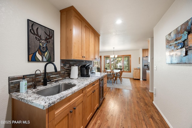 kitchen featuring light wood-style flooring, a sink, a chandelier, stainless steel refrigerator with ice dispenser, and backsplash