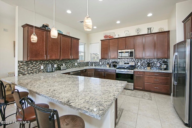 kitchen with a kitchen bar, pendant lighting, stainless steel appliances, and decorative backsplash