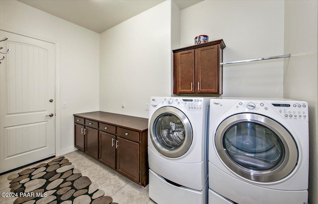 clothes washing area with separate washer and dryer, light tile patterned flooring, and cabinets