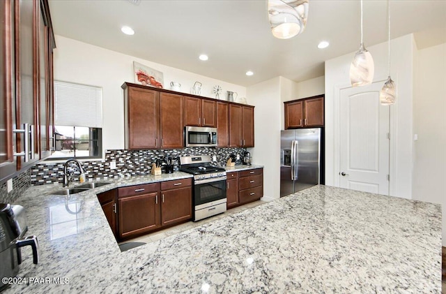 kitchen featuring sink, hanging light fixtures, decorative backsplash, light stone countertops, and stainless steel appliances