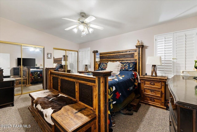 carpeted bedroom with multiple closets, ceiling fan, and vaulted ceiling