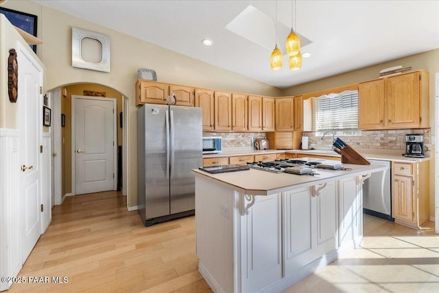 kitchen with light brown cabinetry, decorative light fixtures, lofted ceiling, a center island, and stainless steel appliances