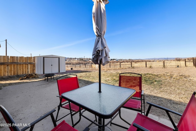 view of patio with a rural view and a storage shed