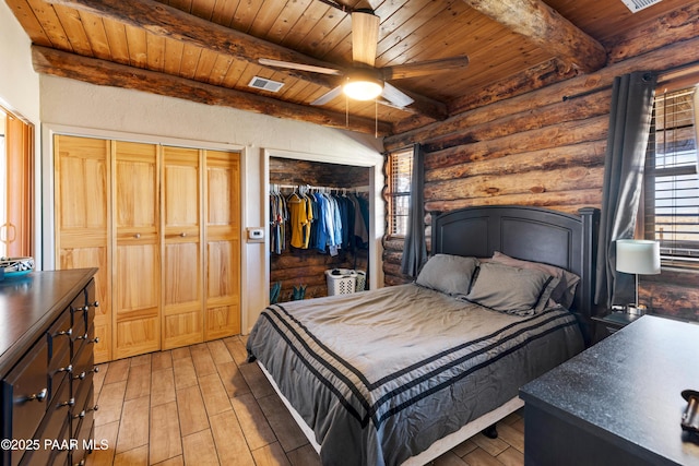 bedroom featuring wood ceiling, ceiling fan, log walls, beam ceiling, and multiple closets