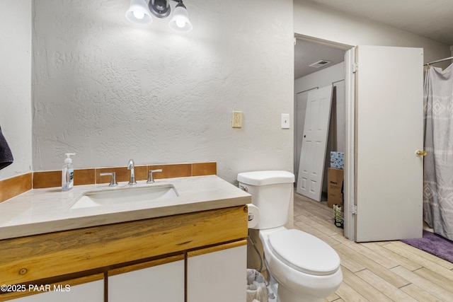 bathroom featuring hardwood / wood-style flooring, vanity, toilet, and walk in shower