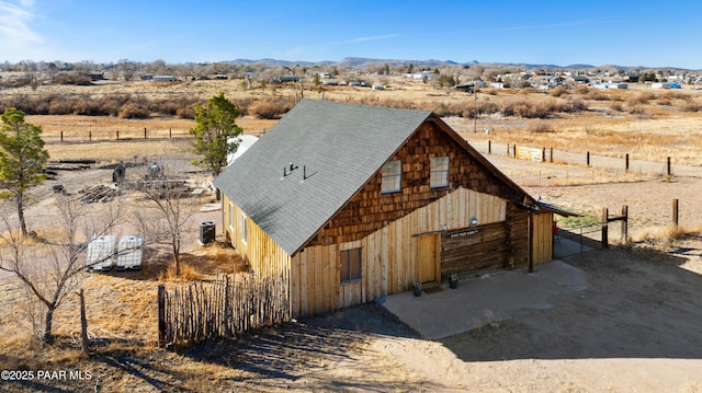 view of front facade featuring a mountain view, a rural view, an outdoor structure, and central AC