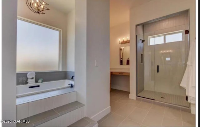 bathroom with a shower stall, a chandelier, baseboards, tile patterned floors, and a garden tub