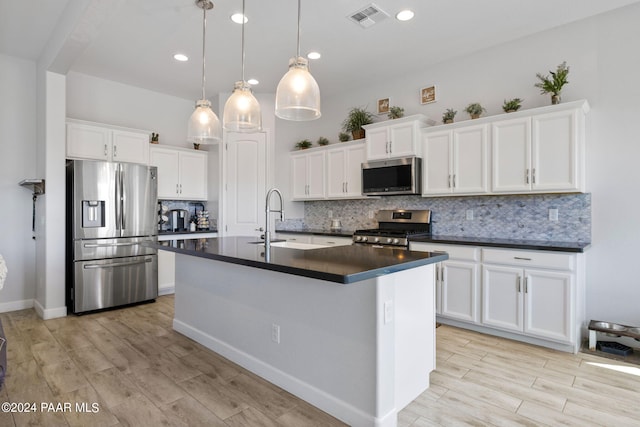 kitchen featuring white cabinets, decorative light fixtures, and stainless steel appliances