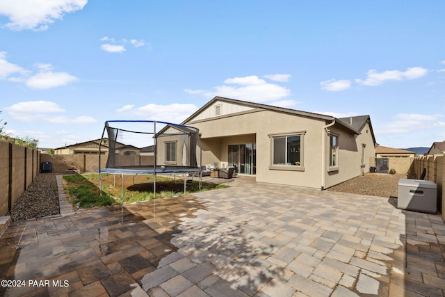 rear view of property with a patio area and a trampoline